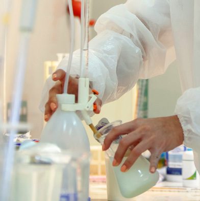 Research and development scientist performing laboratory work with beakers, bottles and tubing